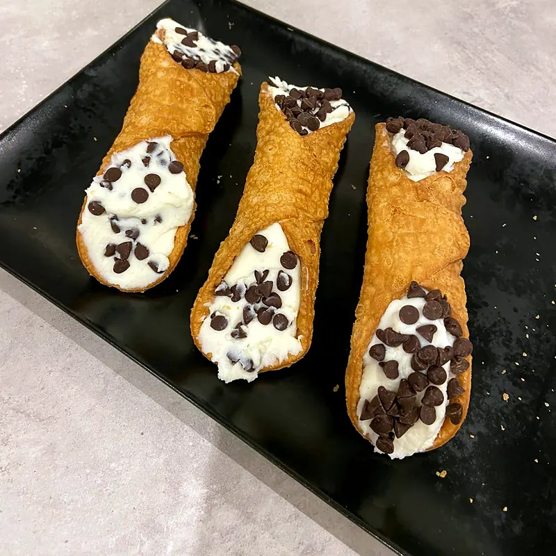 Trois cannoli siciliens croustillants garnis de crème à la ricotta et de pépites de chocolat