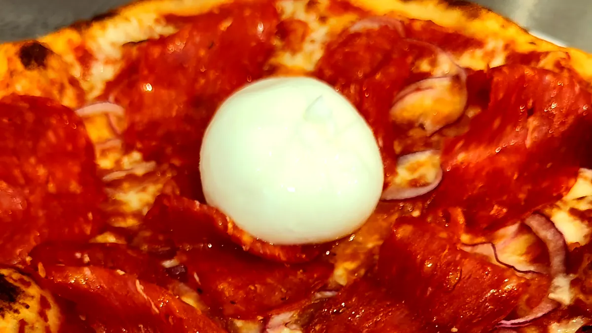 Pizza au salami piquant et oignons rouges, burrata crémeuse au centre, cuite par Mangio Pizza à Saint-Jeoire