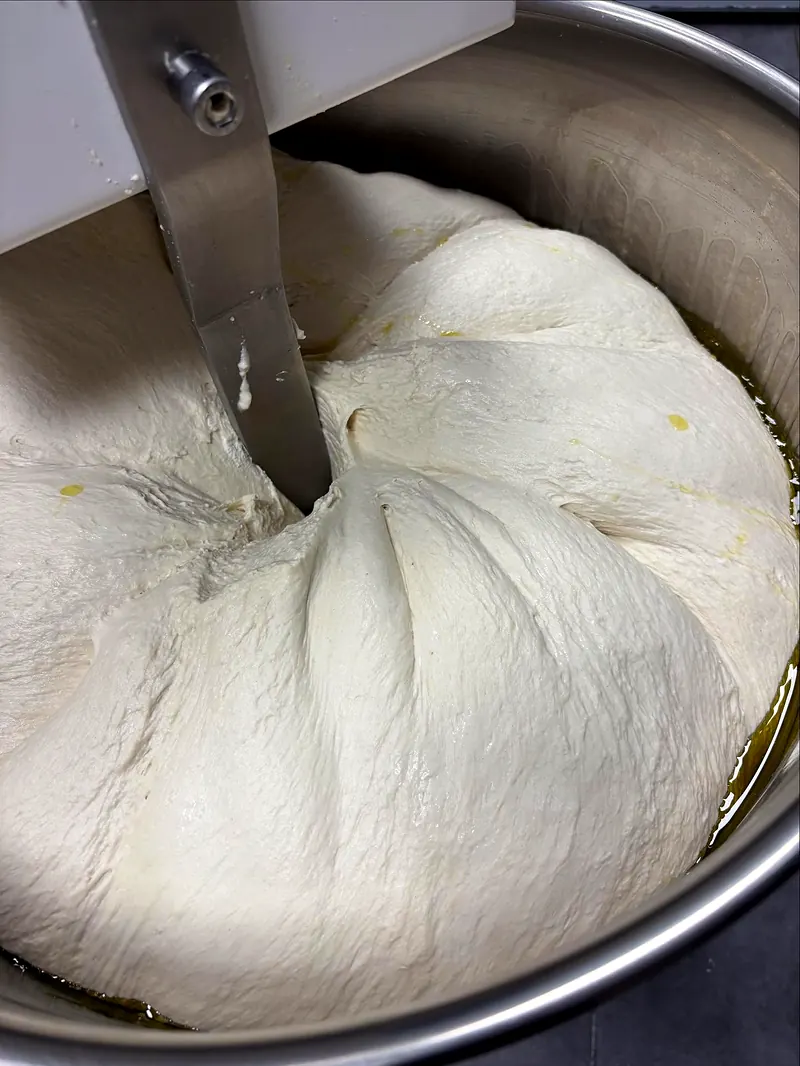 Pâte à pizza en cours de pétrissage dans le pétrin de la pizzeria